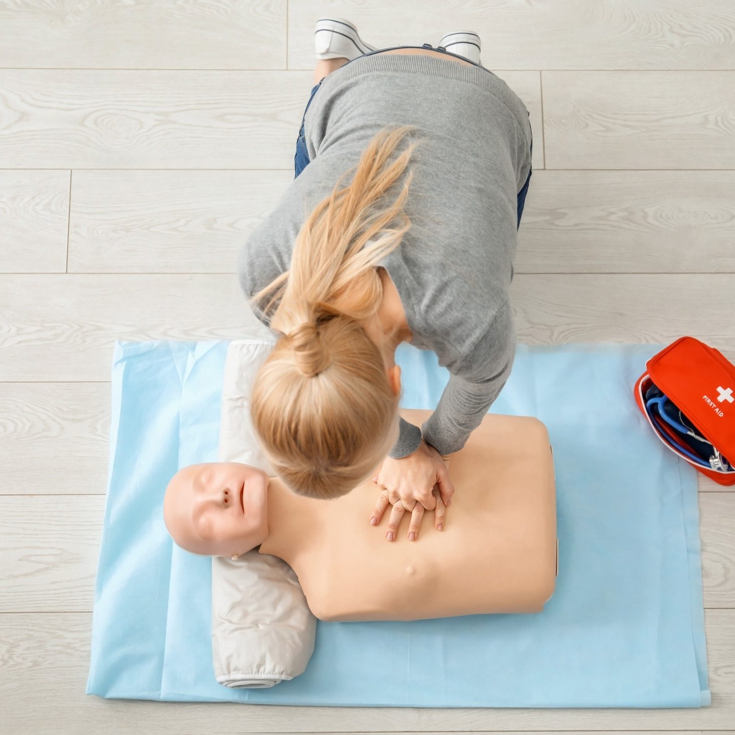 Woman practicing CPR on mannequin at first aid class